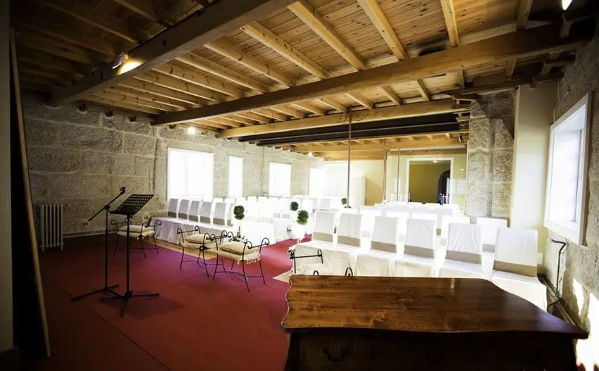 El salón de piedra montado para una ceremonia civil: sillas blancas, un atril, una alfombra roja y una mesa de madera